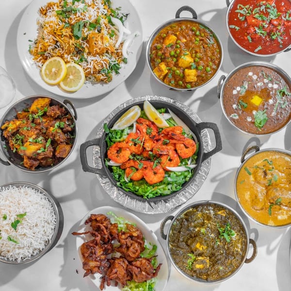 A top-down view of various Indian dishes, including biryani, curries, shrimp, and pakoras.